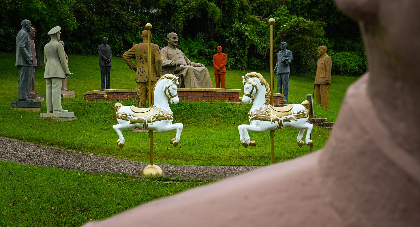 A pair of merry-go-round horses sit among Chiang Kai-shek statues during National Day festivities taking place at Cihu park