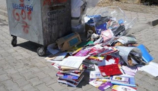 A photograph showing a large bin with an untidy pile of textbooks next to it.
