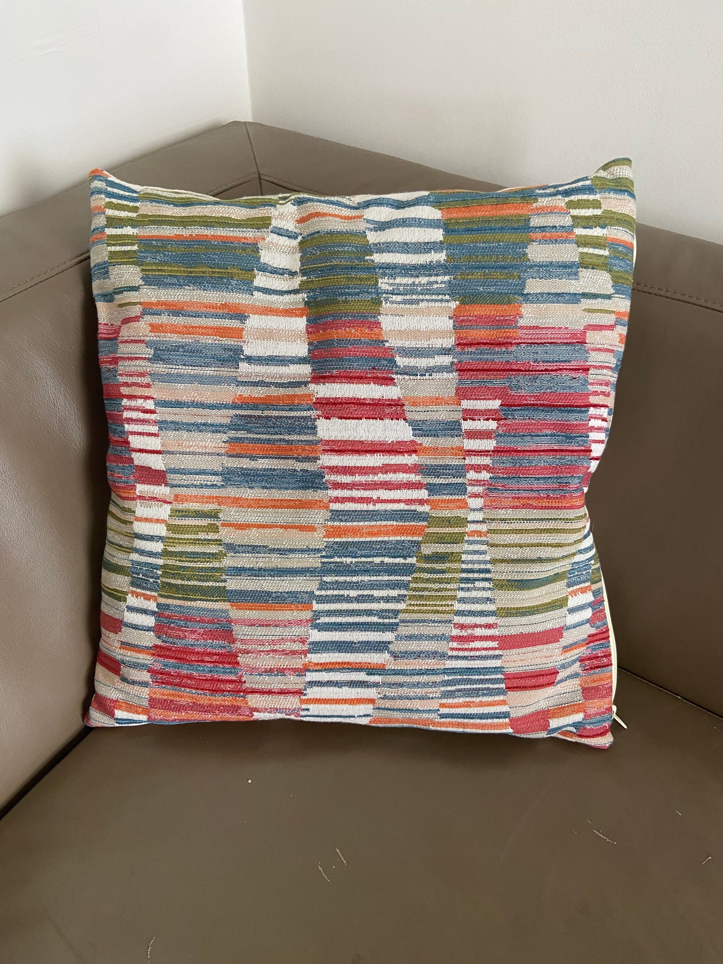 a throw pillow with a pattern of earth toned stripes in wavy triangles. 