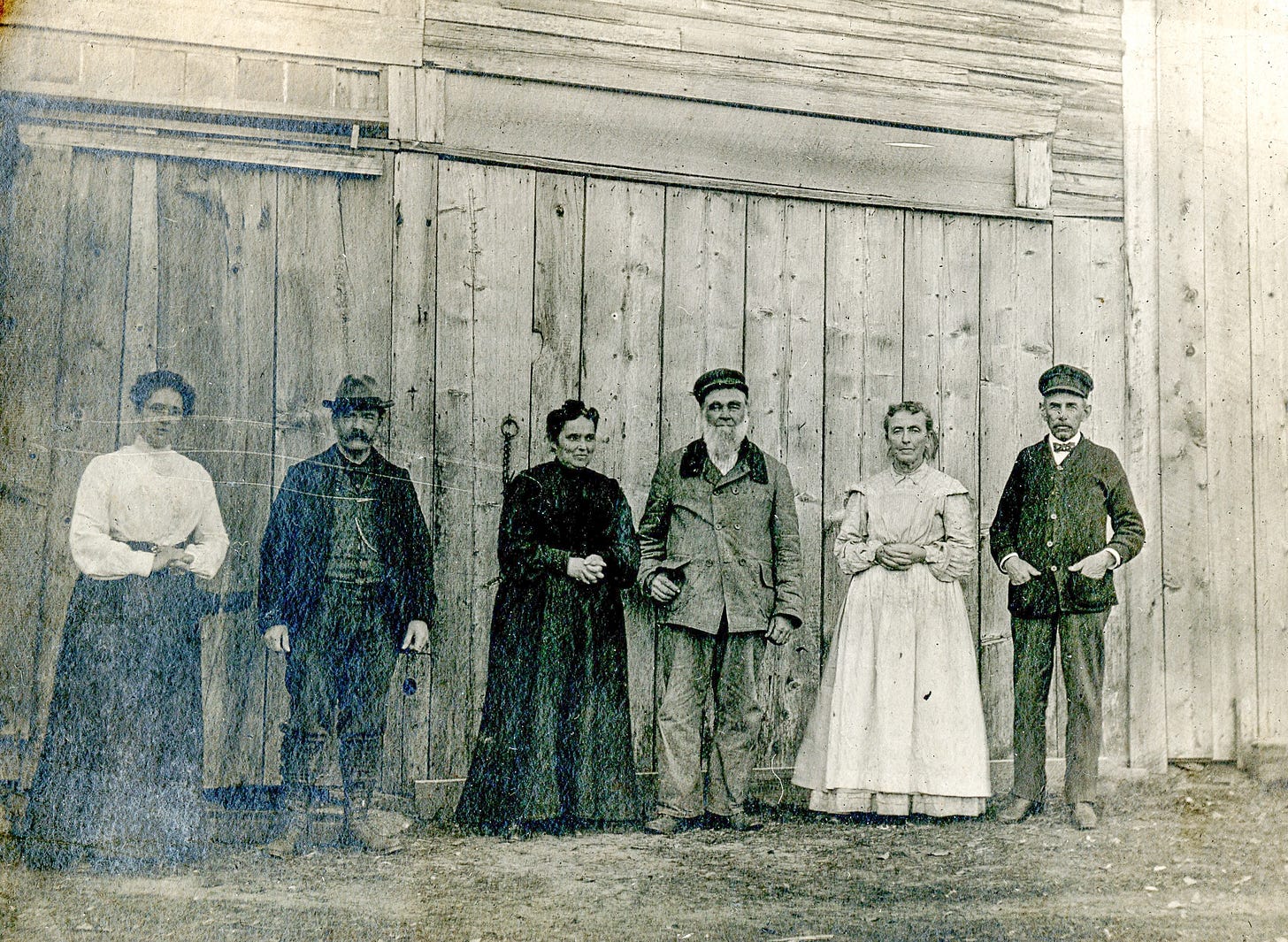 Six people standing in front of a barn