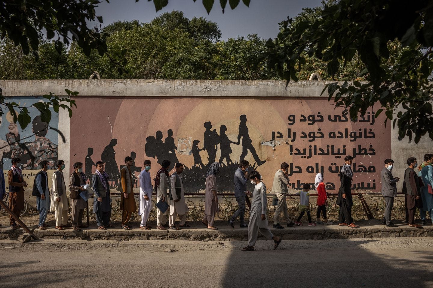 Afghans waited in line for the Kabul passport department, in front of a mural warning against migration, in July.