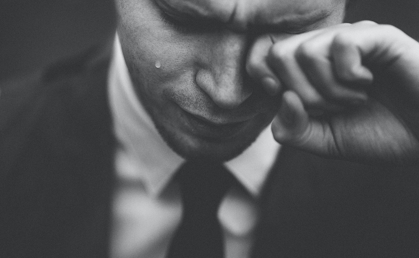 A man in a suit and tie crying.
