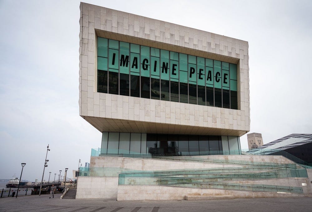 gray concrete building with Imagine Peace signage at daytime