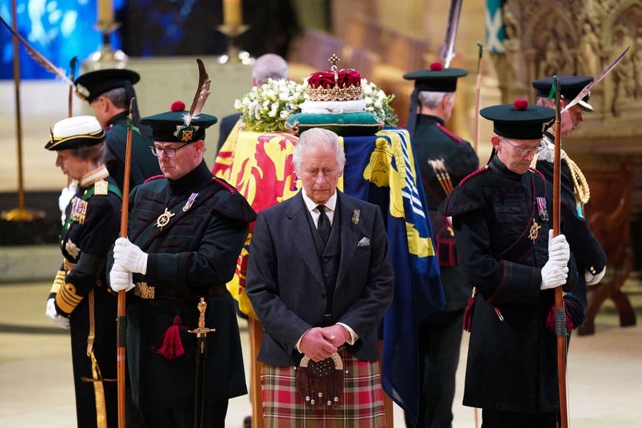 Britain's King Charles III and other family members and soldiers stand in a circle around a coffin.