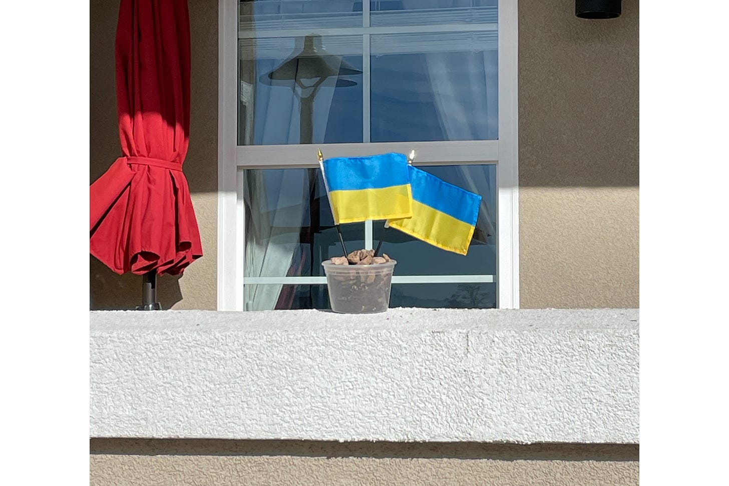 two small ukrainian flags in a container on a porch