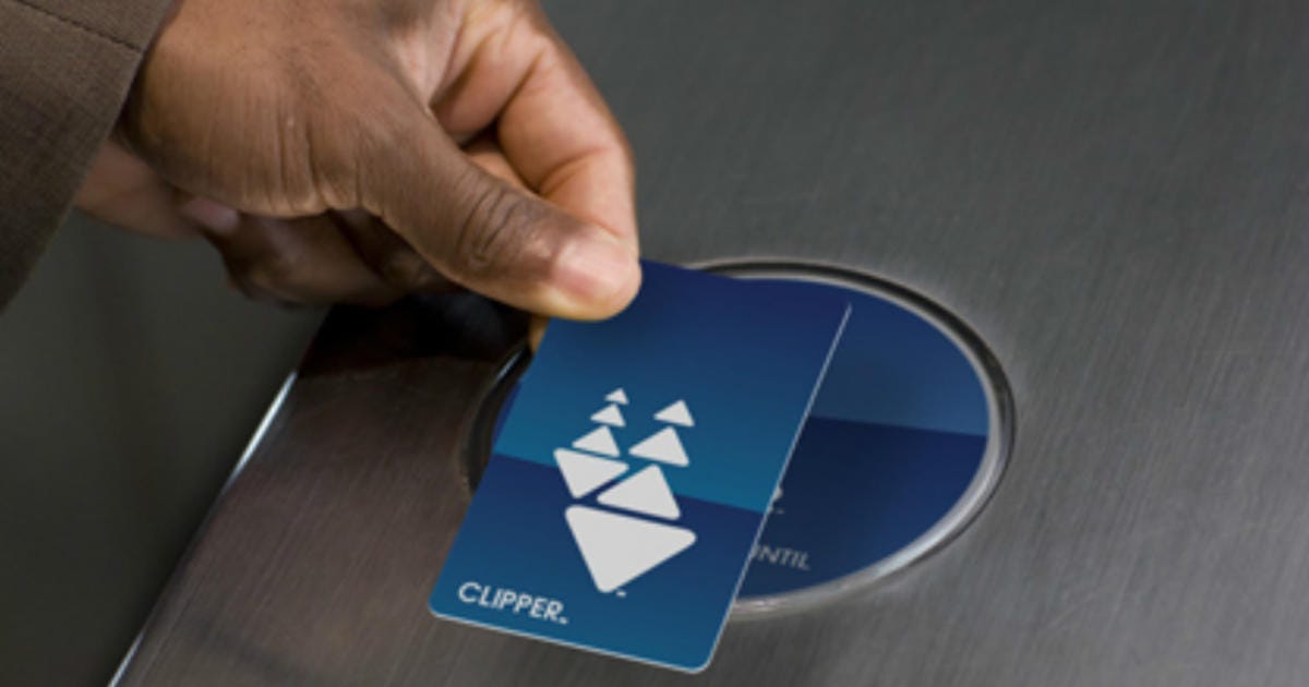 A hand holding a Clipper card to a scanner