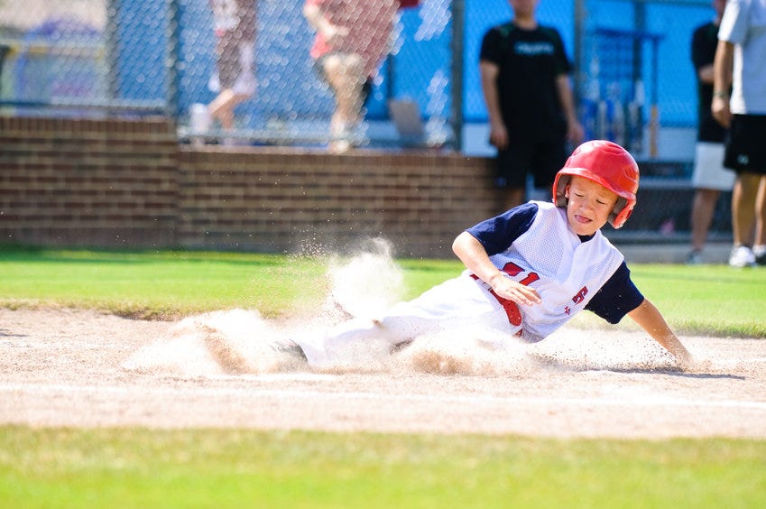 Youth baseball player sliding into a base