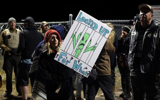 A woman carries a sign outside a gate to Area 51.