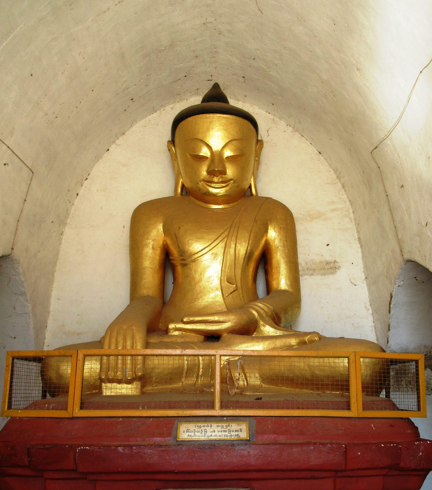 A golden seated Buddha in an alcove photo taken in Myanmar in 2018