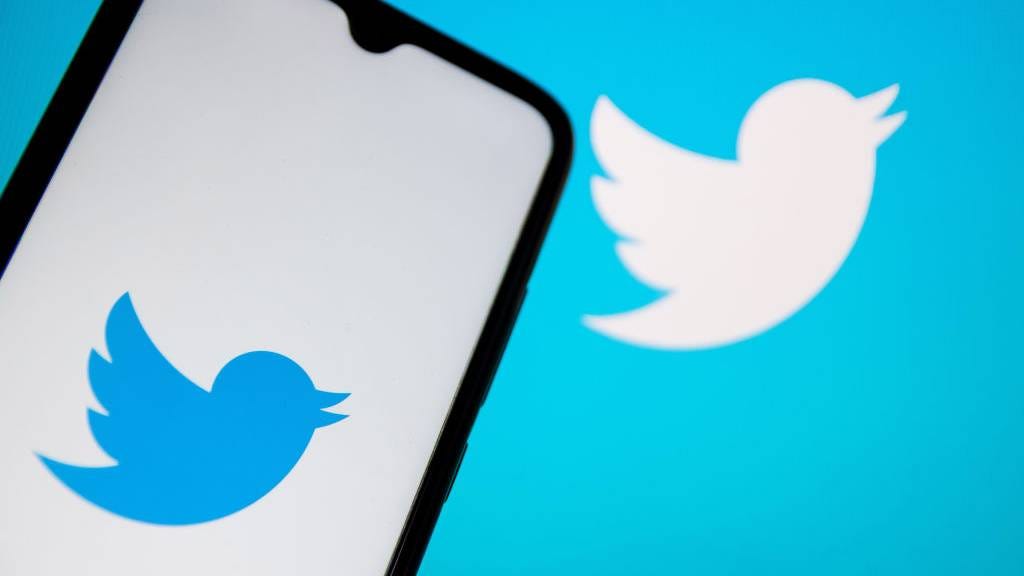 Twitter logo on a phone and in the background