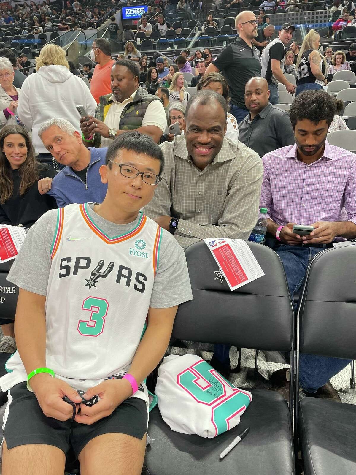 Taro  Kotani, 41, sitting beside Spurs great David Robinson at a game.