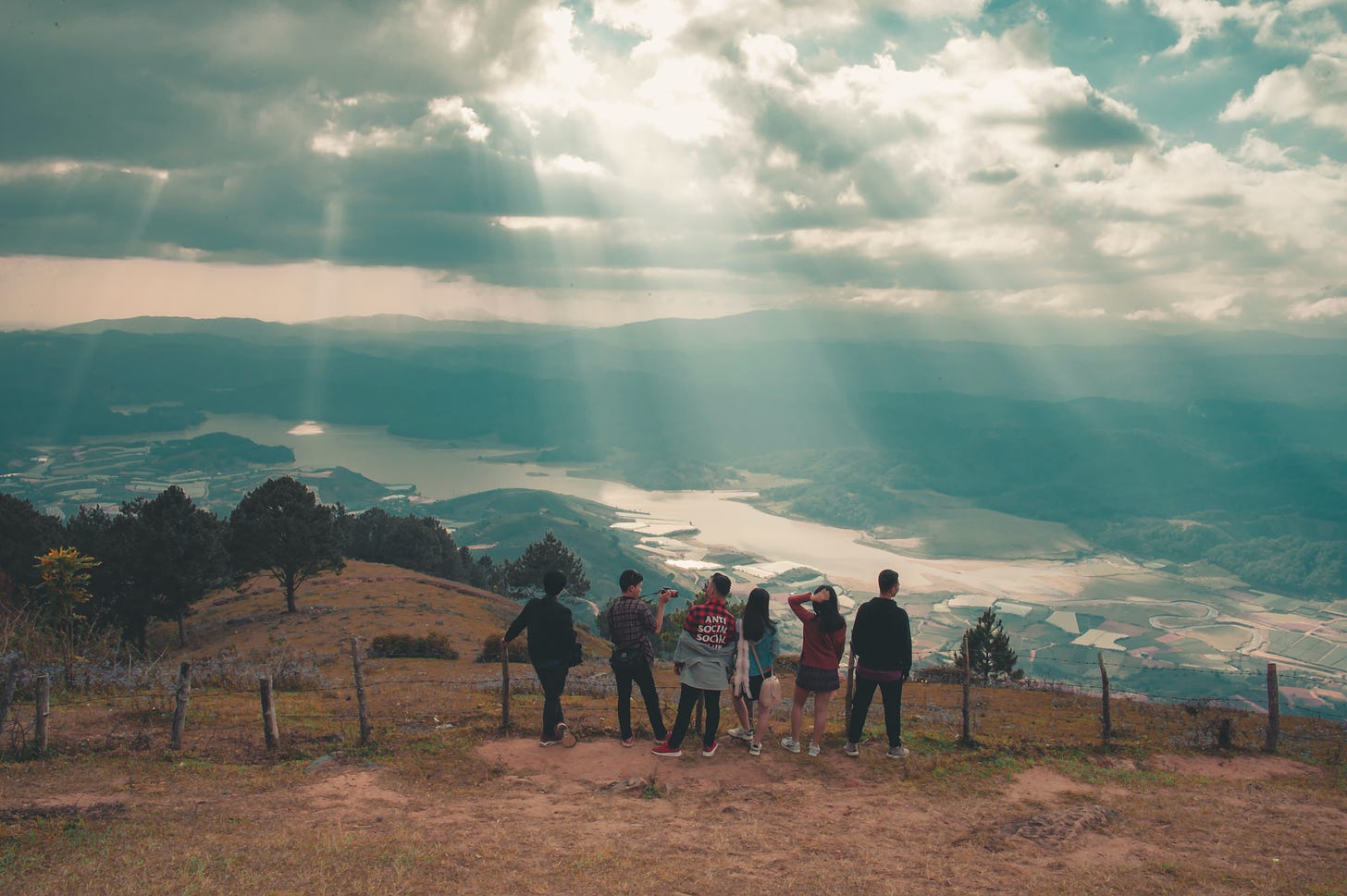 A group of people standing on a hill overlooking a valley.