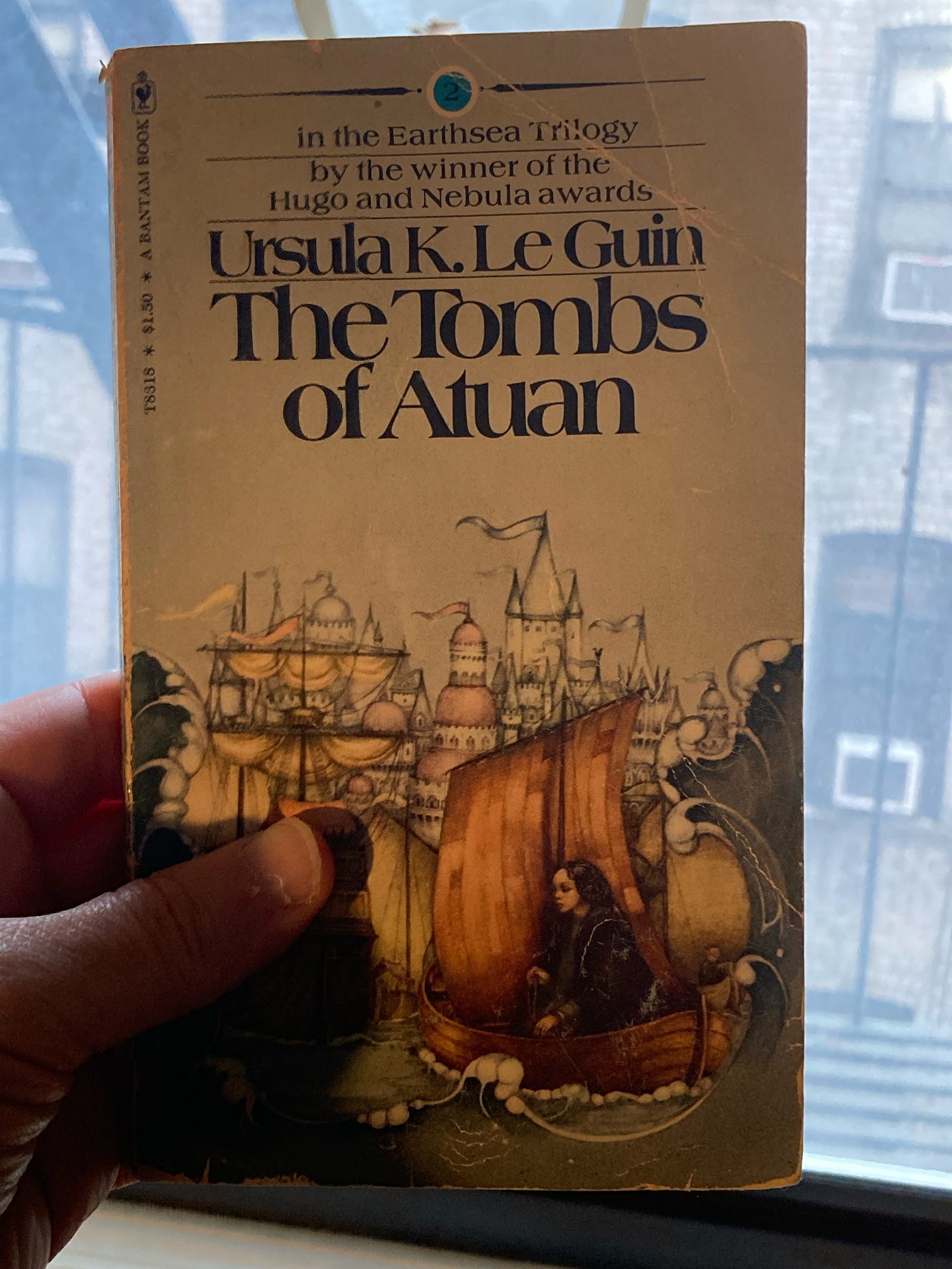 a battered paperback copy of The Tombs of Atuan