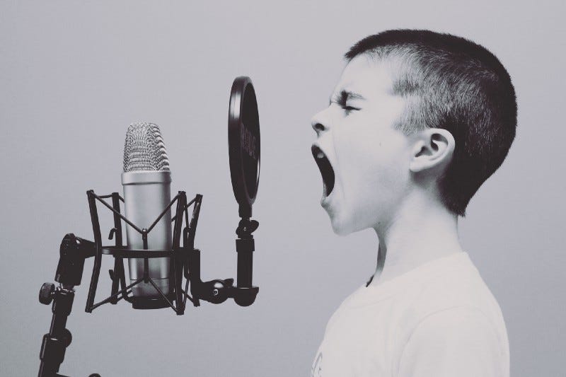 A boy shouts into a microphone.