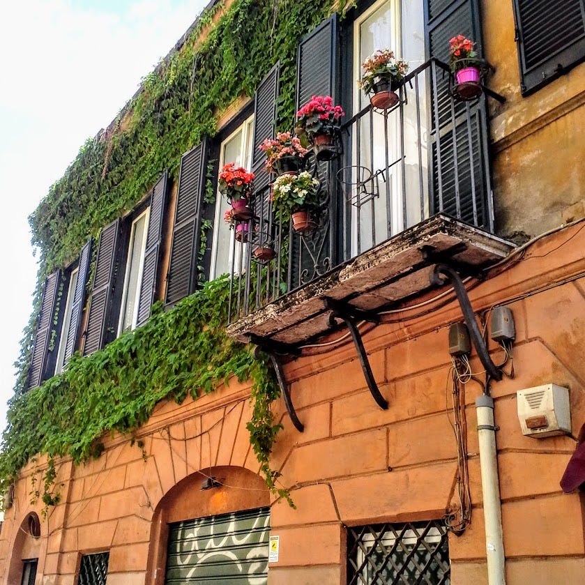 Flower pots hang from balconies of a residential building in Rome.