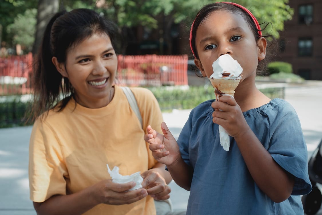 Asian happy mother looking at daughter eating ice cream