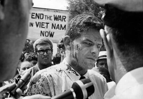 Mr. Lynd in a black and white photo. He is in the middle of a crowd with one person holding a protest sign behind him. 