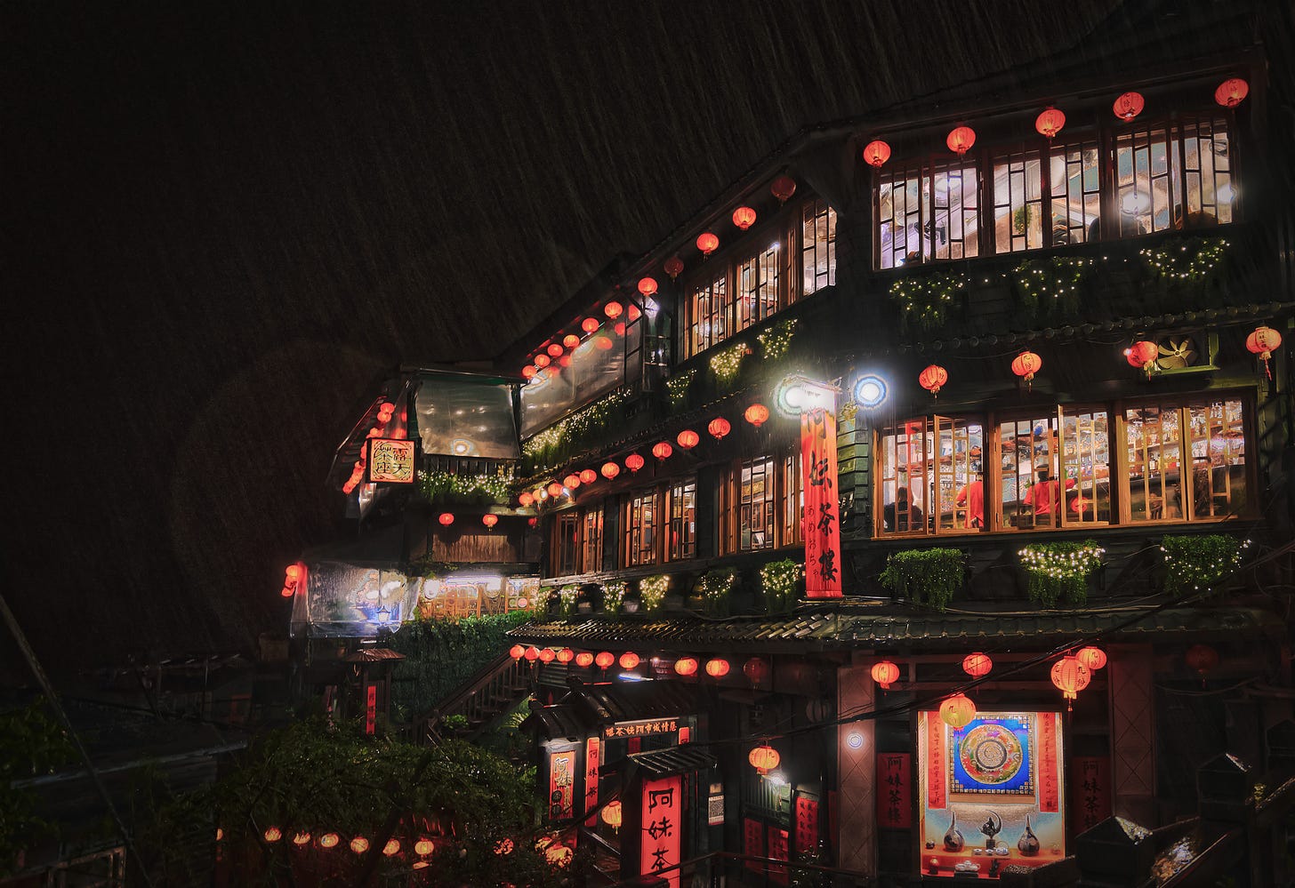 The glowing windows and red lanterns of Jiufen's iconic Amei Teahouse 阿妹茶樓 seen through heavy nighttime rain
