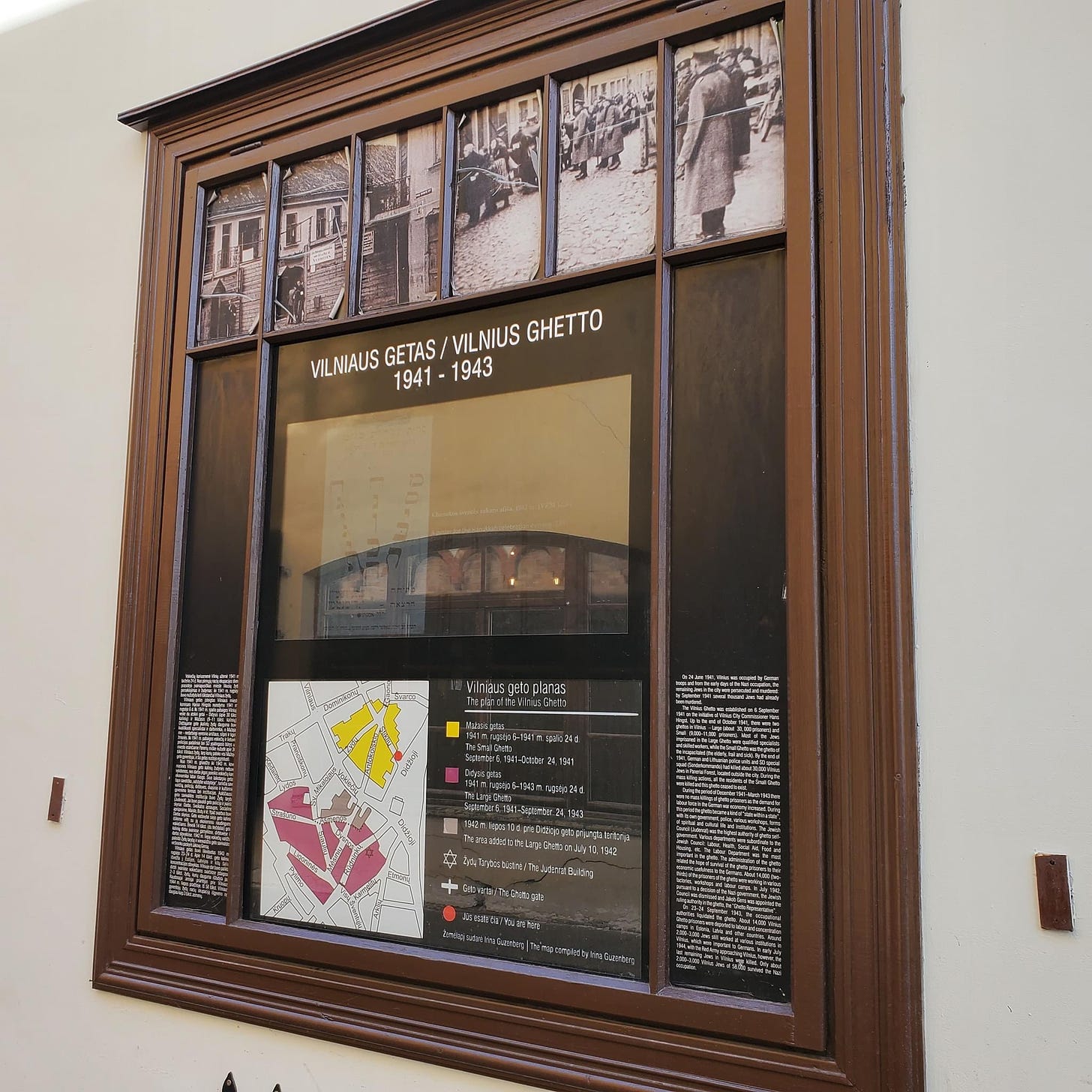 Sign in wooden frame with photos and writing in several languages. 