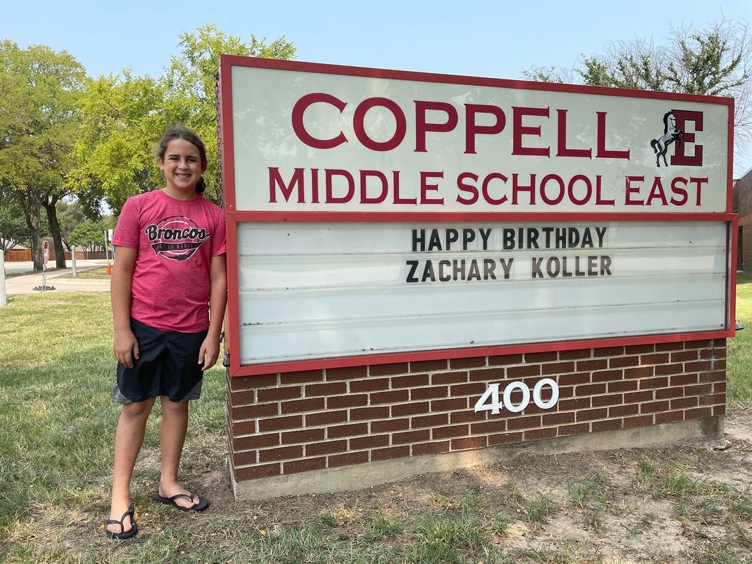 A boy standing next to a sign bearing a birthday message in front of Coppell Middle School East