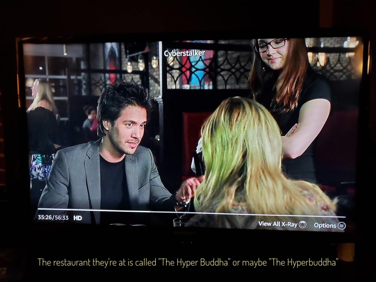 Paul, a stubbly white guy with big hair, eating dinner with Aiden, captioned "The restaurant they're at is called 'The Hyper Buddha' or maybe 'The Hyperbuddha'"