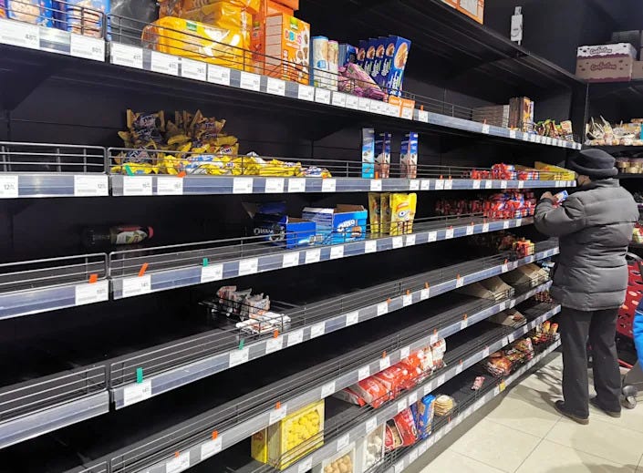 Largely empty shelves are seen at a supermarket as one person shops.