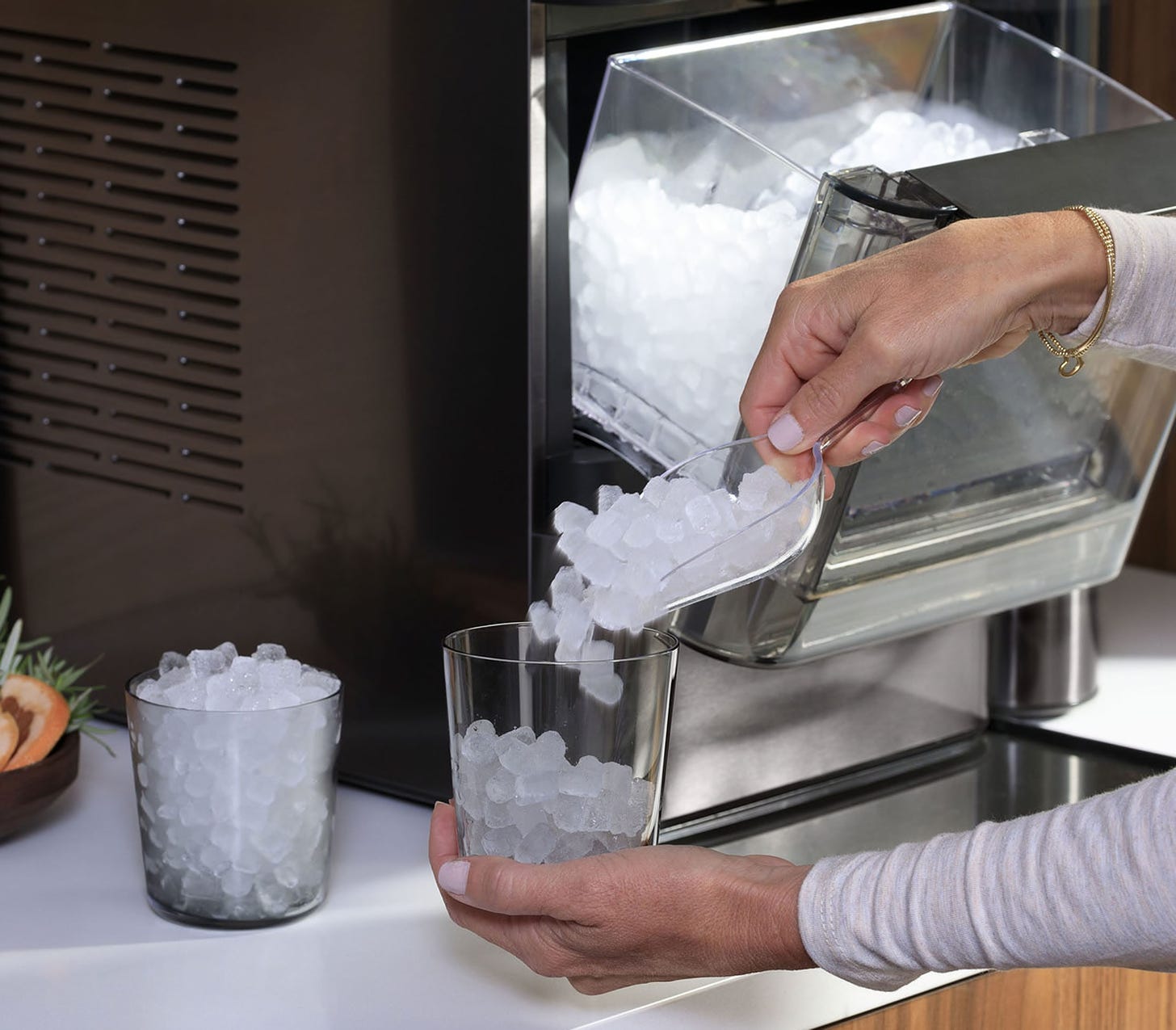 A hand pouring pellet ice into a glass from an ice machine