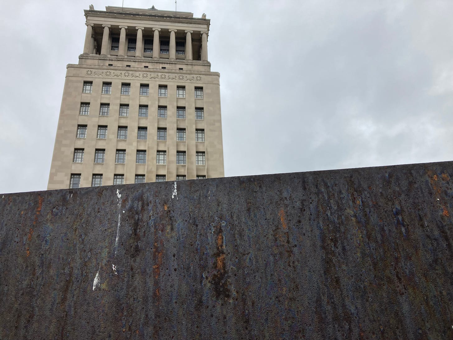 The St. Louis Civil Courts building rises behind the dark, rusting wall of Richard Serra's "Twain" sculpture