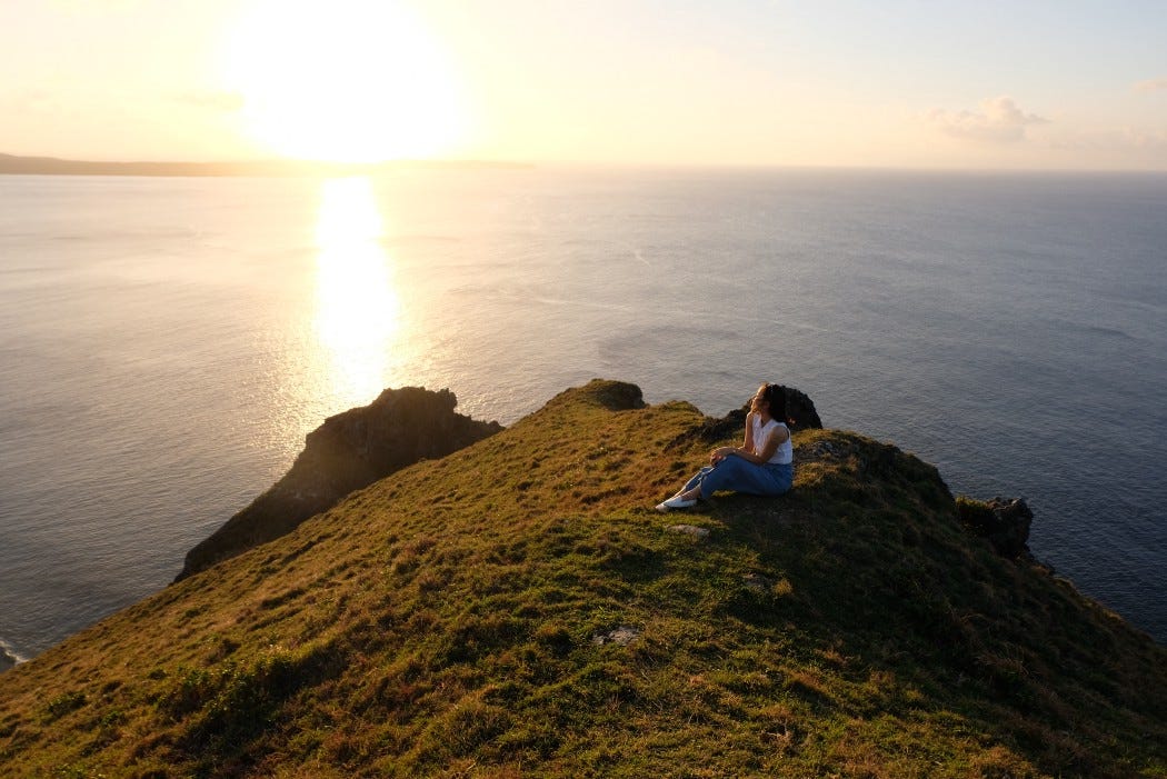 A girl watching the sunset from a hill