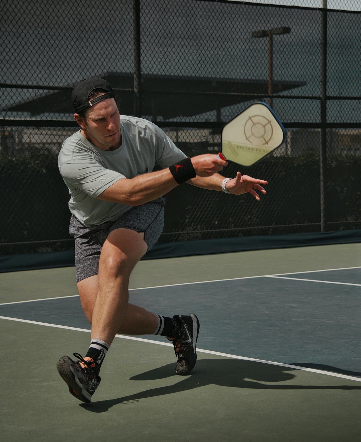 An athletic male steps forward while swinging a pickleball paddle. An athletic male steps forward while swinging a pickleball paddle.