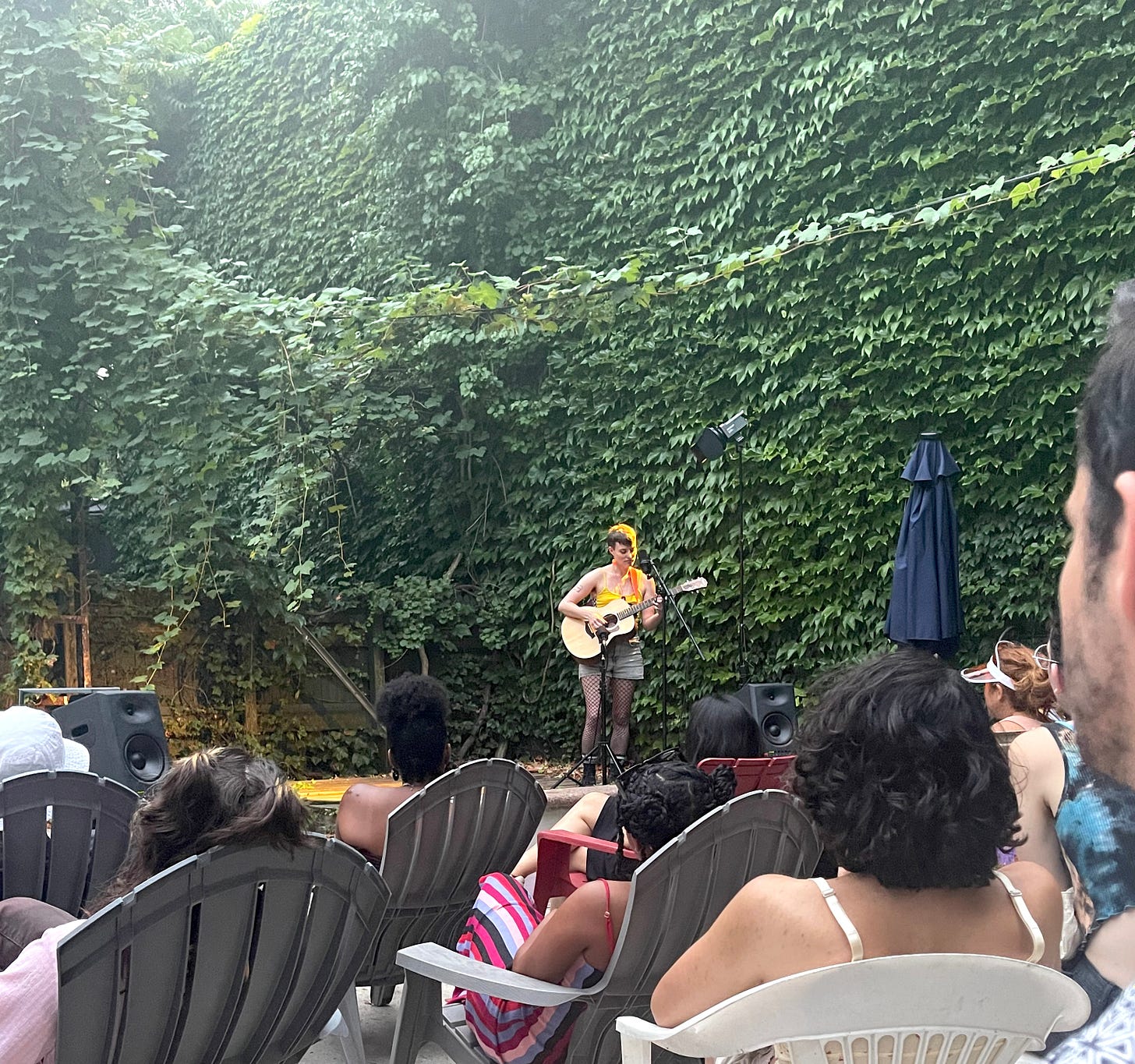 Cassidy Dawn Graves performing with acoustic guitar at Queers N Peers Spitroast