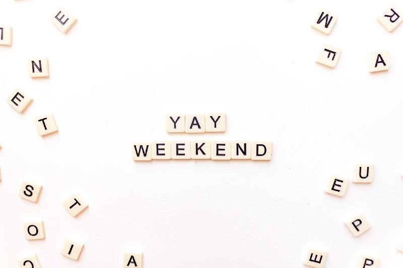 An arrangement of alphabet letter pieces forming the phrase "Yay Weekend" surrounded by other random letters