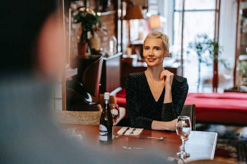 Woman at dinner with friend looking at him from across the table.