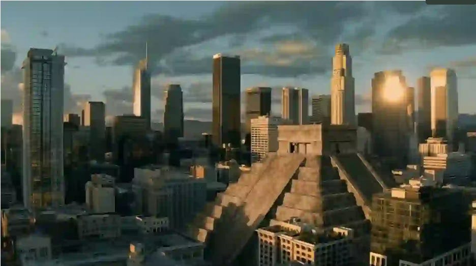 Descrição de imagem: Print de um frame do clipe, uma imagem colorida a céu aberto de uma cidade cheia de prédios. No meio, uma pirâmide Inca se destaca. 