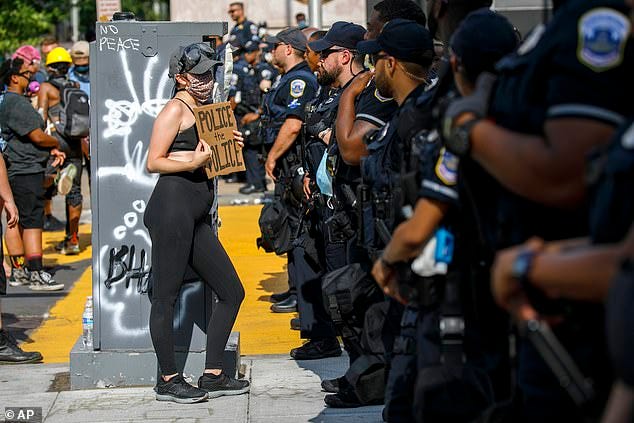 She held up a up a sign saying 'police the police' as she confronted a police line during a protest on a section of 16th Street that has been renamed Black Lives Matter Plaza