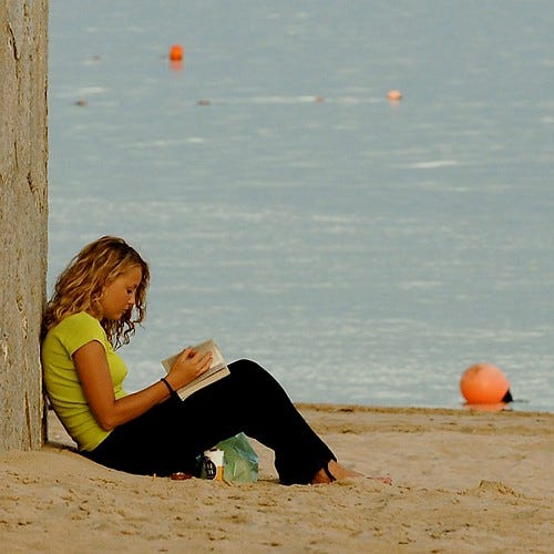 "Girl reading at the beach" by pedrosimoes7 is licensed under CC BY 2.0.