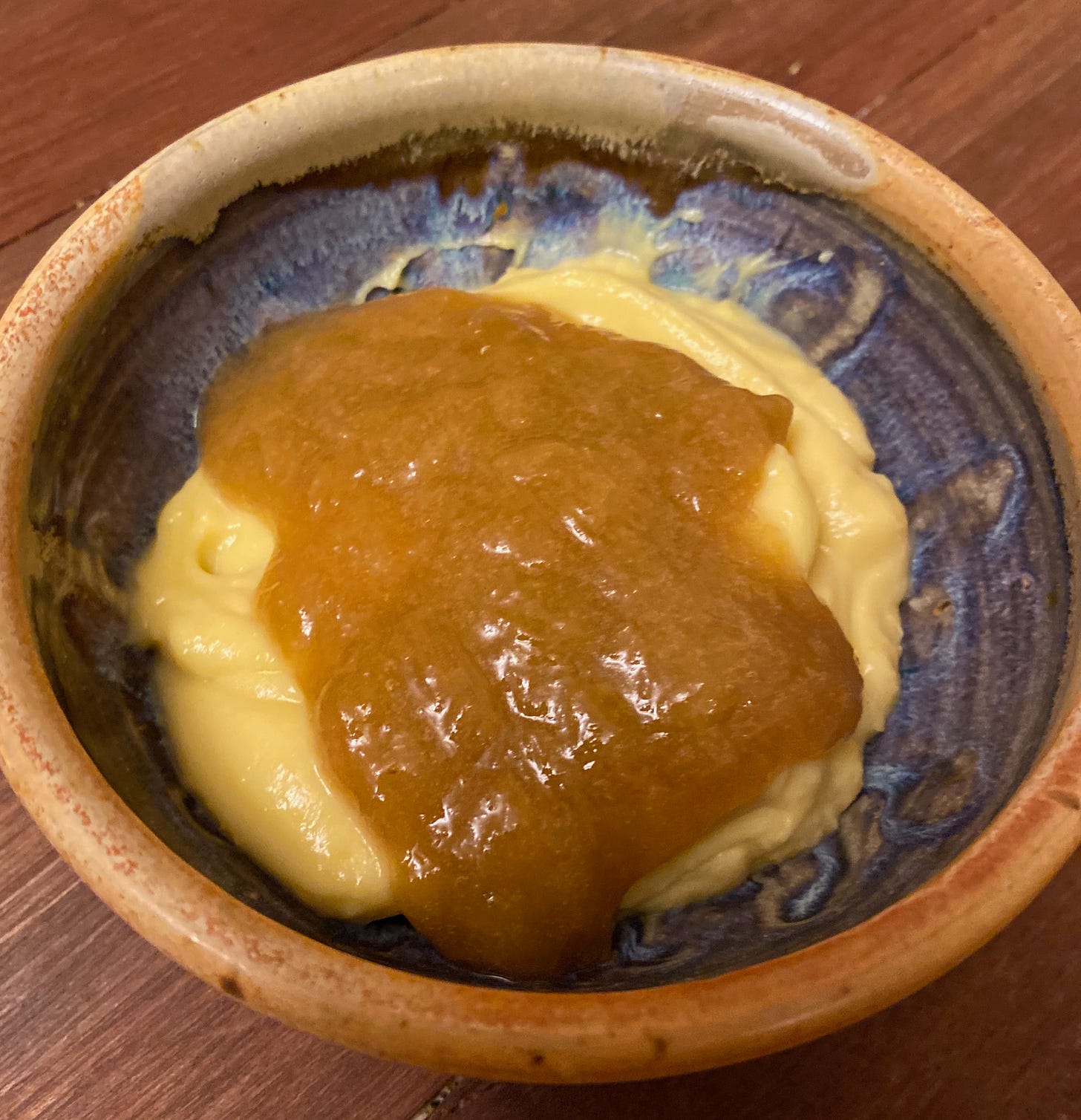 A small ceramic bowl of vanilla custard topped with rhubarb compote.