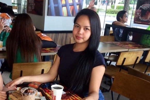 A brown haired woman smiles while seated at a table