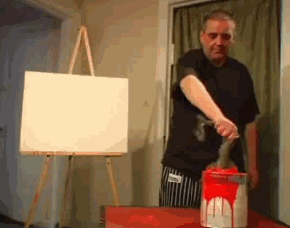Man splashing red paint on a canvas, while looking at a more masterful work of art.