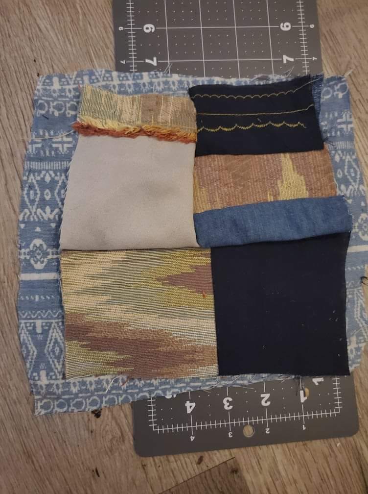 An image of quilt pieces on a cutting board. The fabric and cutting board are on a wooden floor. 