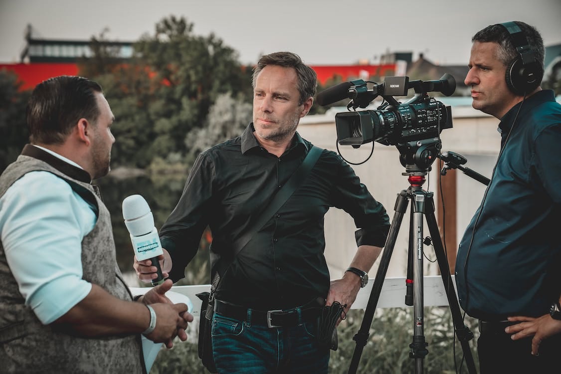 Free Man Holding Microphone While Talking to Another Man Stock Photo