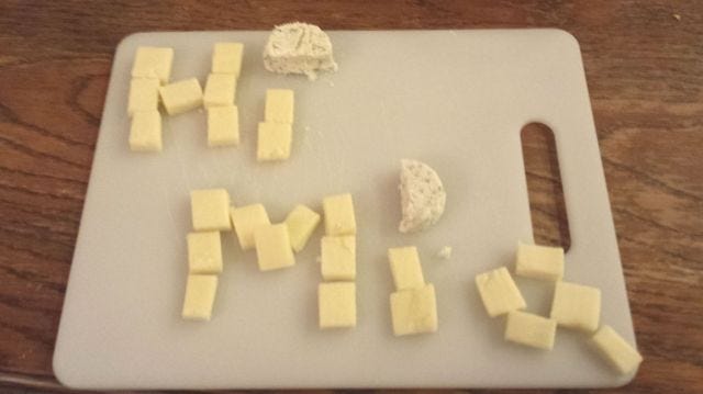 A kind of sad cheese board that says "hi mia"