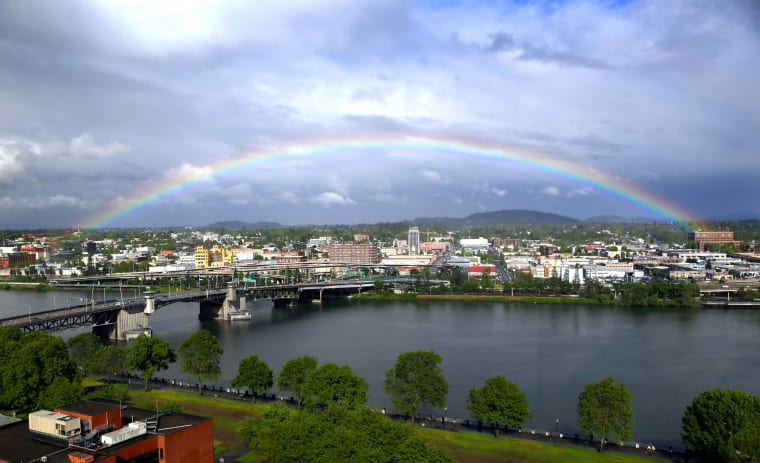 A rainbow pops out under dark rain clouds over the Willamette River in downtown Portland, Ore., on May 11, 2017.