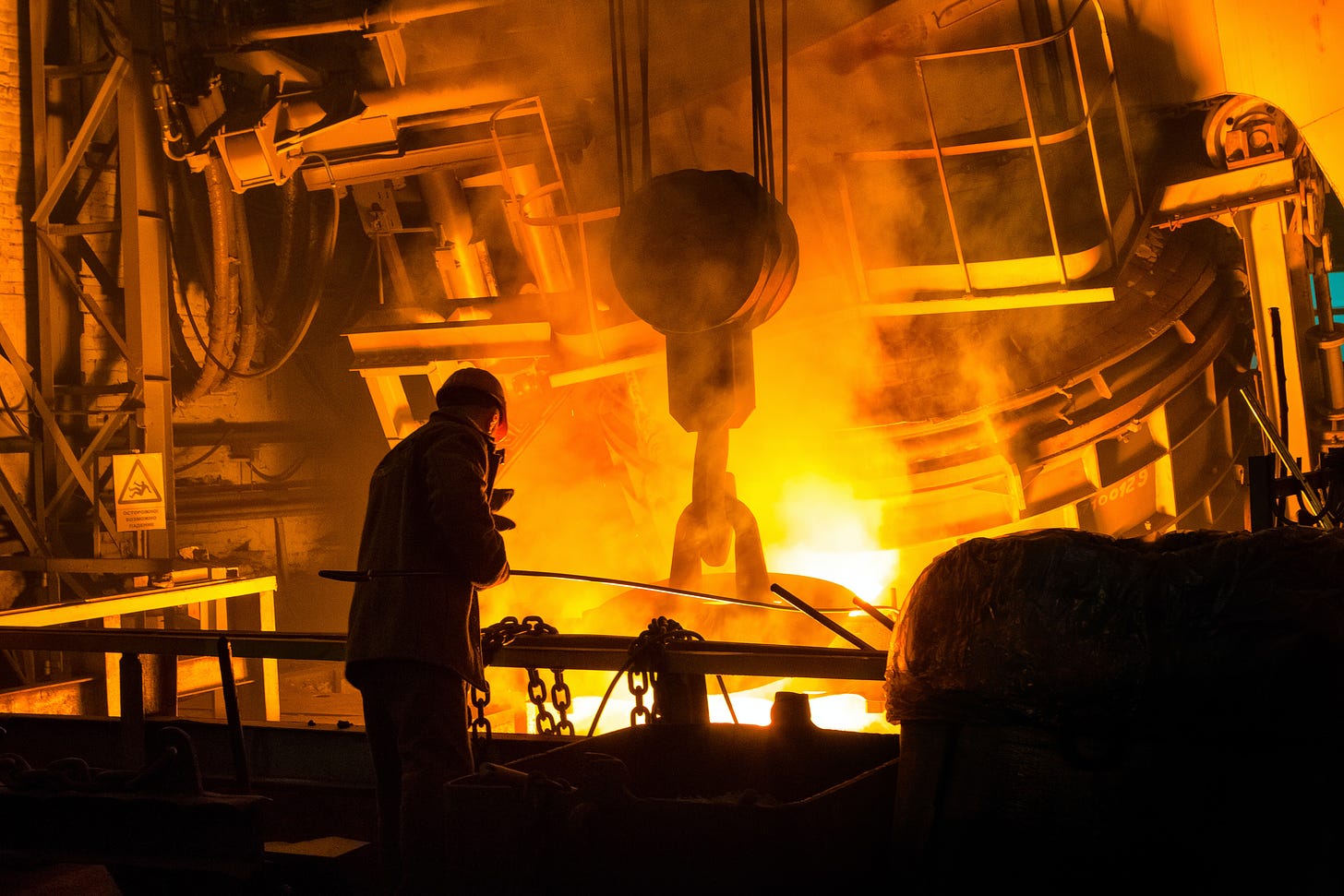 A man operates an industrial forge.