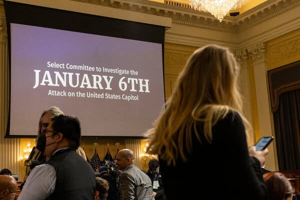 The text “Select Committee to Investigate the January 6th Attack on the United States Capitol” appears on a large screen in a congressional hearing room.