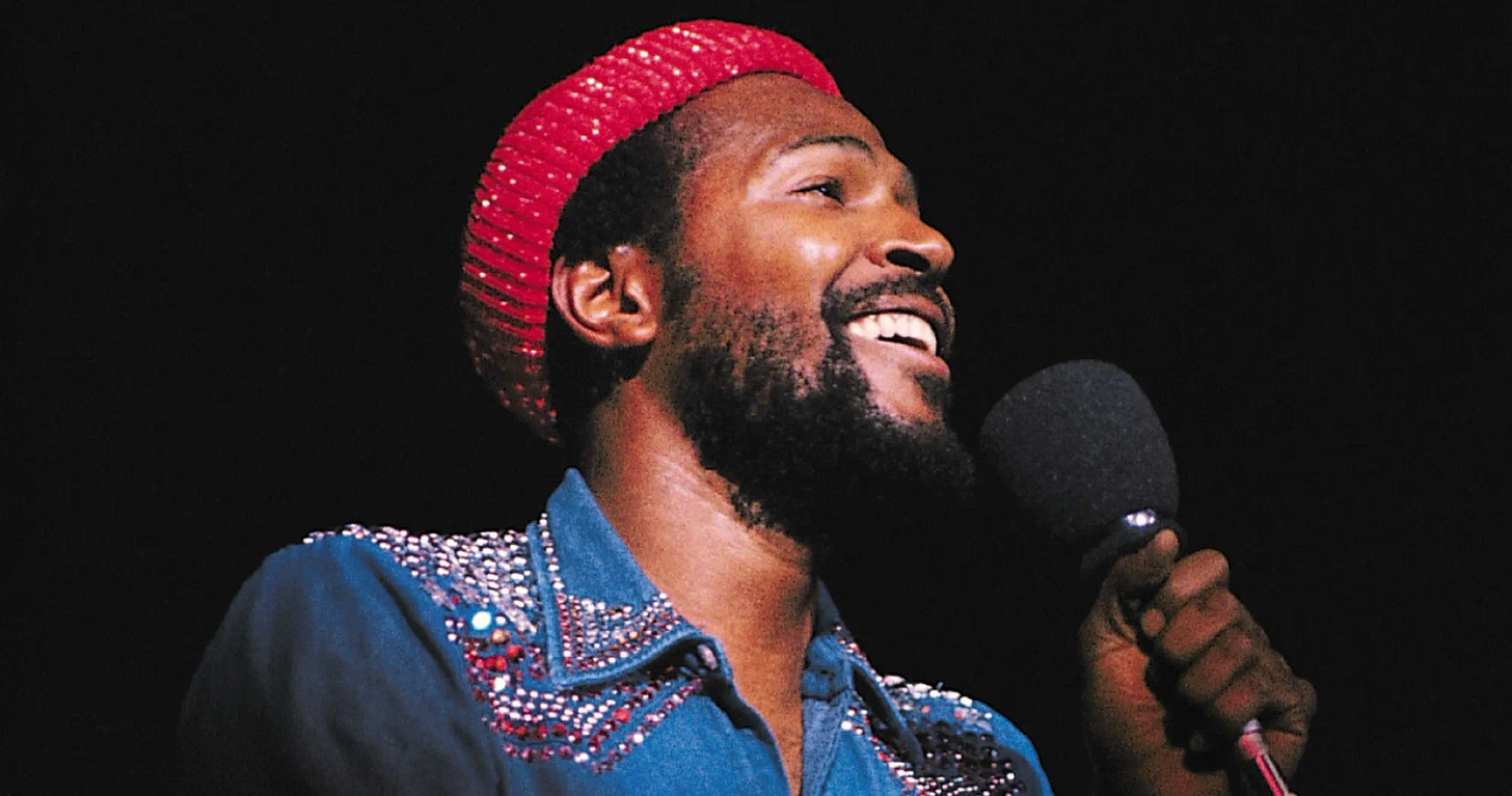 This image shows Marvin Gaye singing onstage at a 4 January 1974 concert given in California's Oakland Coliseum. Gaye wears a red, beret-style cap and a blue shirt with spangles on its shoulders and collar. This image shows Marvin Gaye singing onstage at a 4 January 1974 concert given in California's Oakland Coliseum. Gaye wears a red, beret-style cap and a blue shirt with spangles on its shoulders and collar.