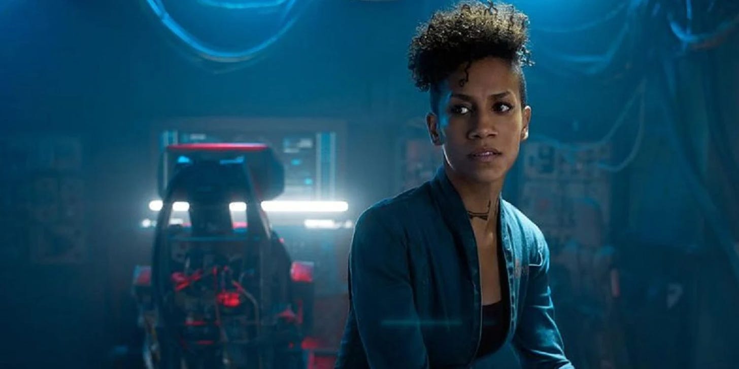 Naomi Nagata from The Expanse sitting in her ship, with a work station in the background behind her