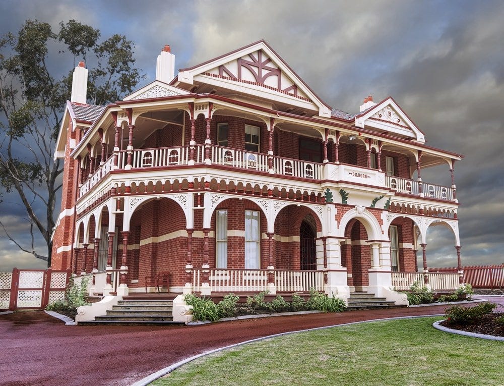 This is a red Quuen Anne Victorian home with wrap-around porch and arches.