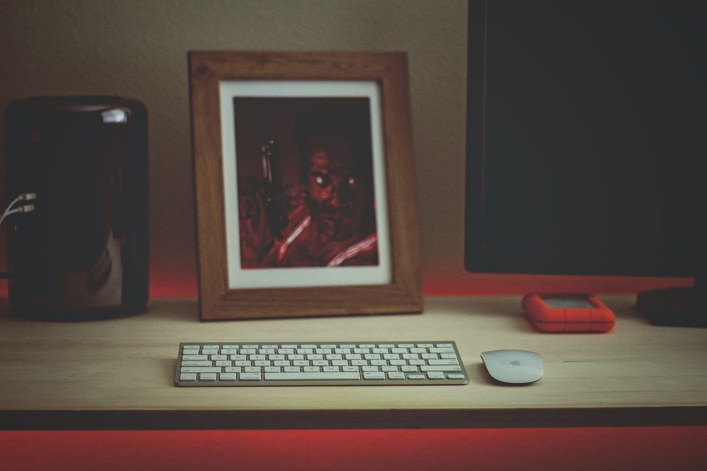 A framed picture of John McClane in Die Hard, next to a computer monitor and behind an Apple keyboard and mouse