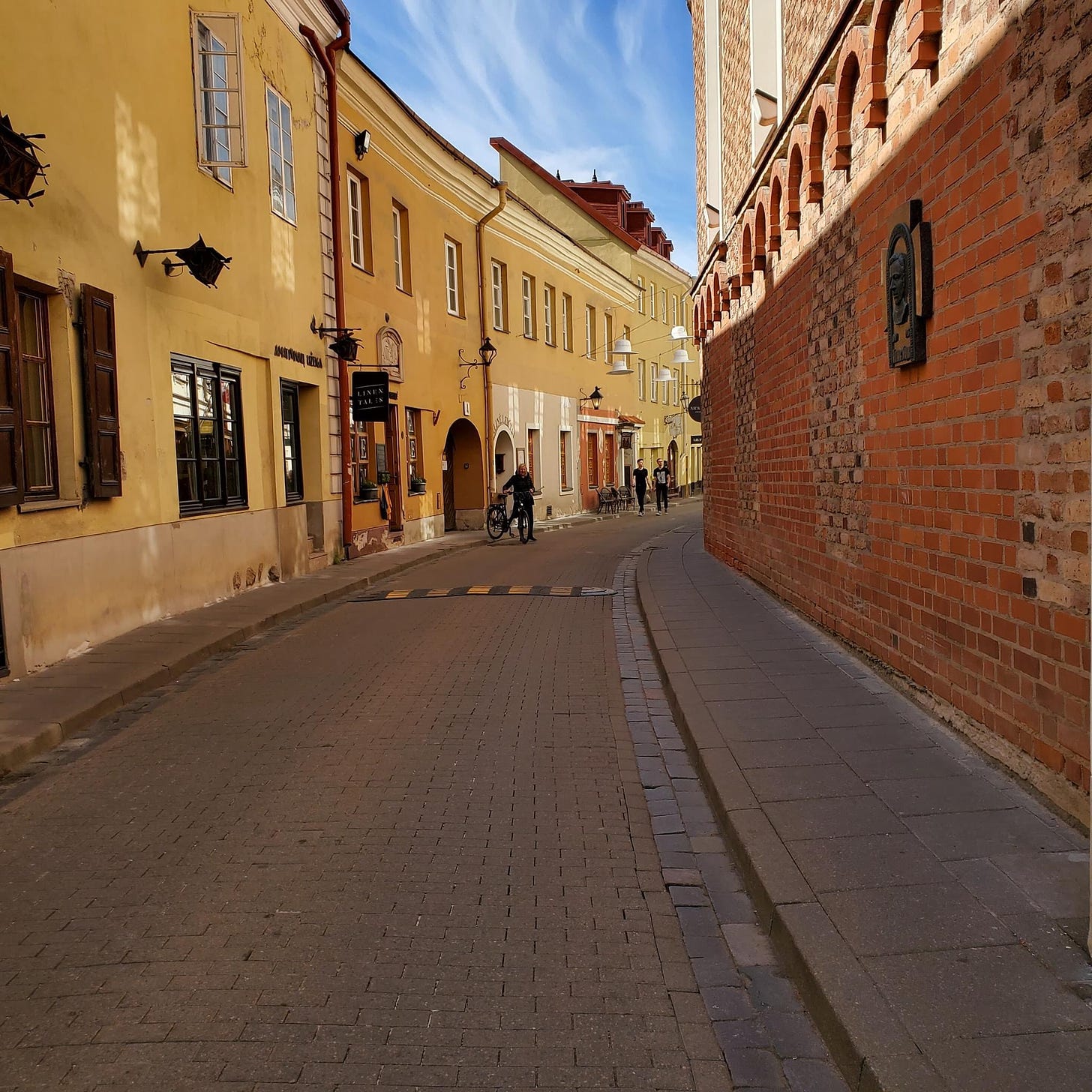 Brick and plaster buildings in the European style line a curved cobblestone street.